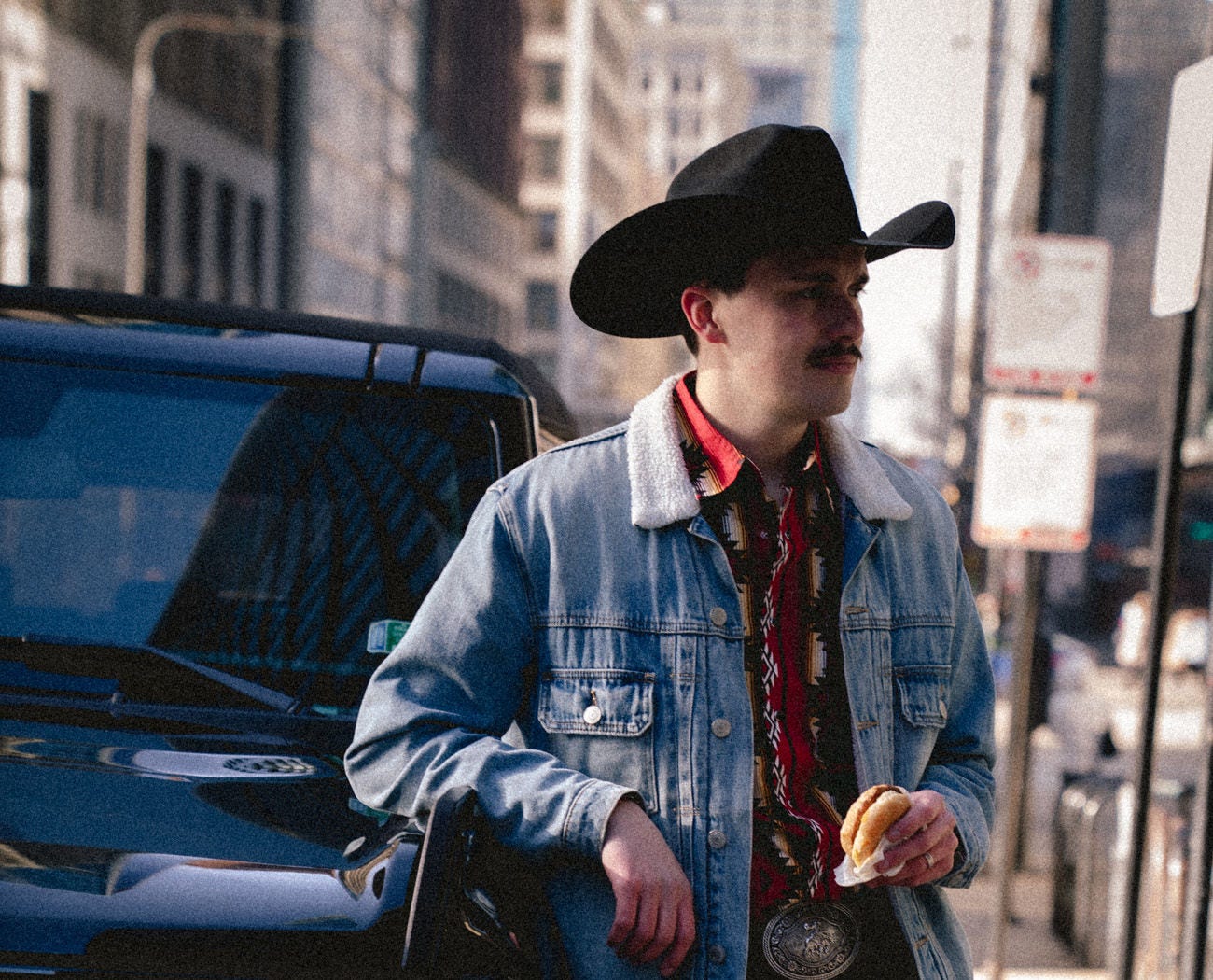 Man in cowboy attire holding a Jimmy Dean breakfast sandwich